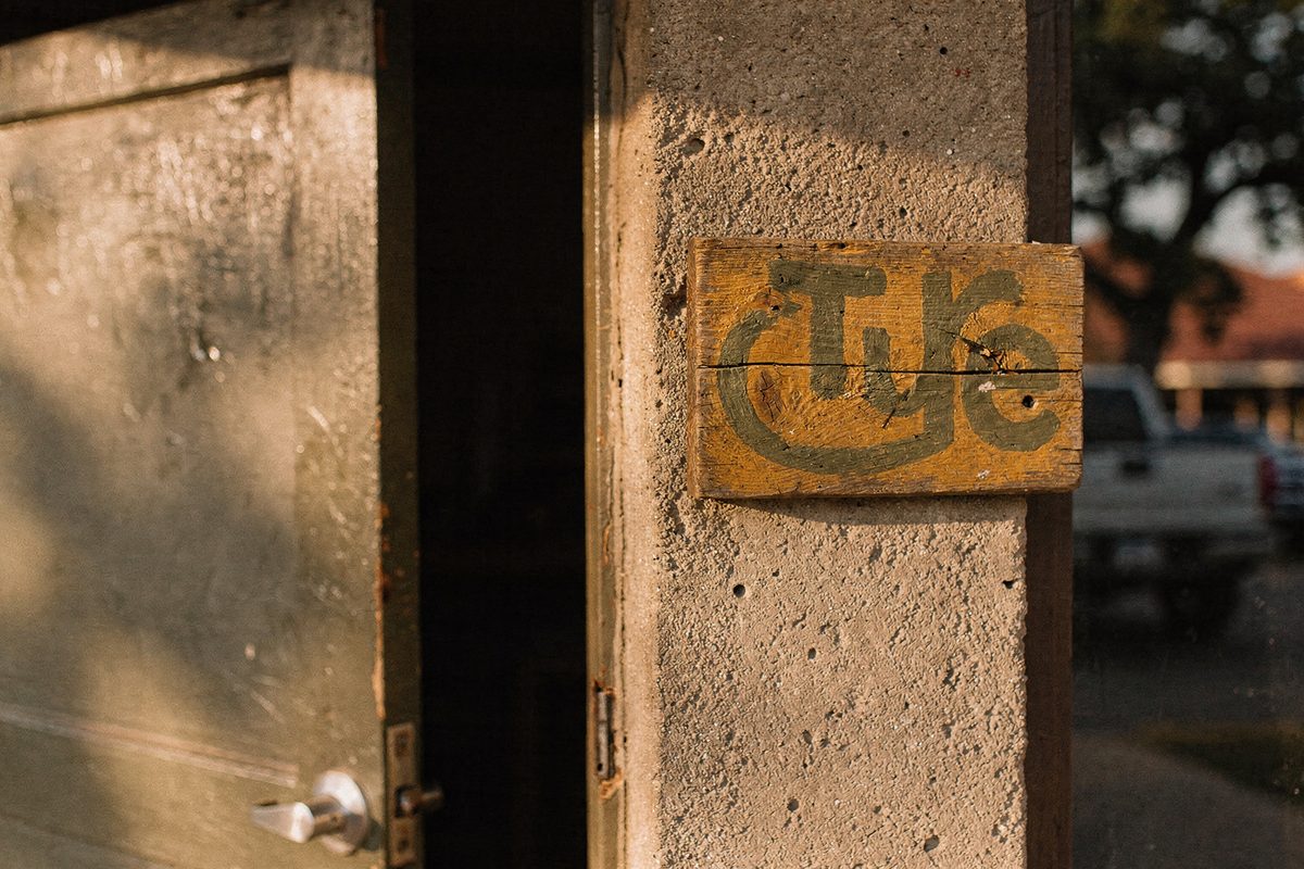 The studio's small painted wooden nameplate sign mounted beside its entrance door.