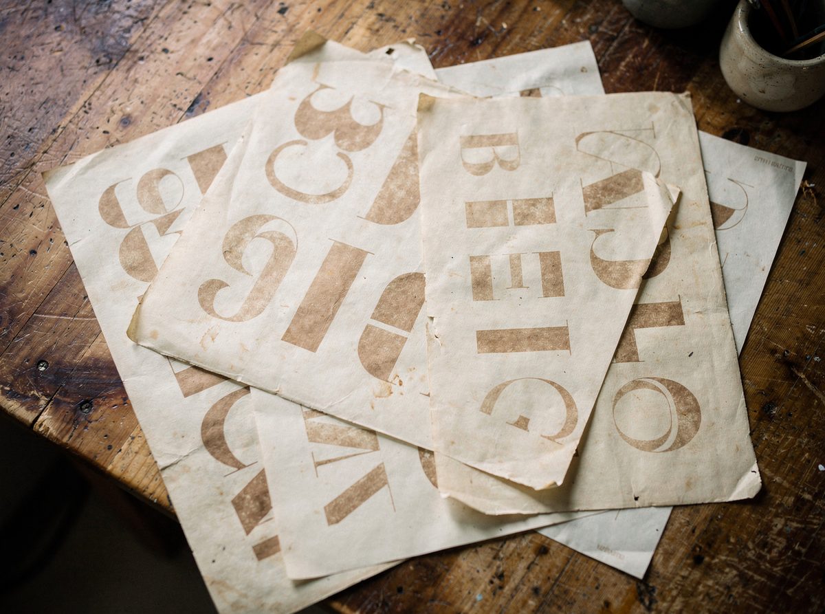 Several printed type specimen sheets overlapping on a wooden table.